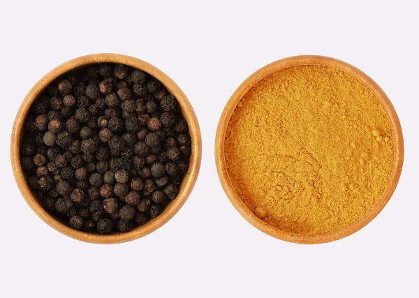 Black pepper and turmeric spices in a wooden bowl showing health benefits